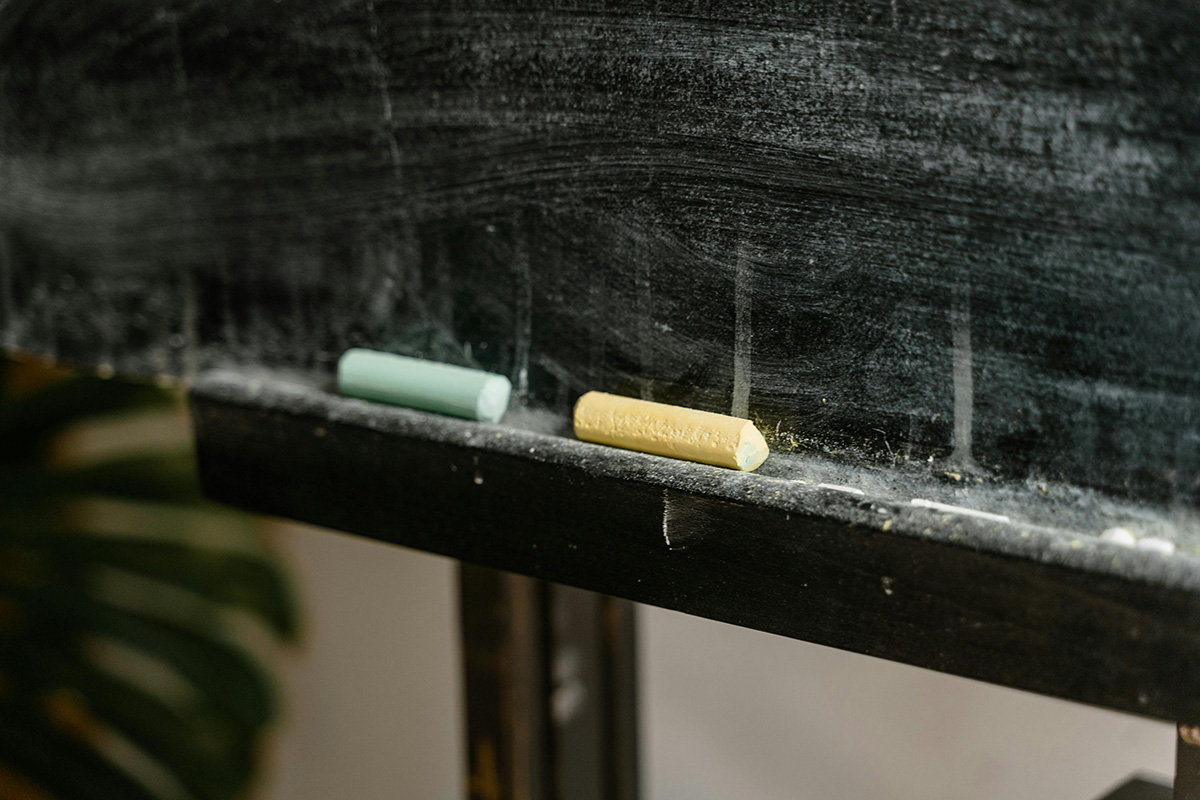 Chalk pieces on a blackboard ledge, symbolising traditional chalk-and-talk maths teaching in the classroom